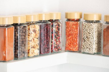 Farklı aromatik baharatlar kavanozlarda, beyaz raflarda, kapalı mekanlarda.