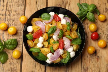 Sarı domatesli lezzetli salata, fesleğen, soğan ve ahşap masada mozzarella peyniri.