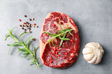 Gri desenli masada çiğ et ve baharat var.