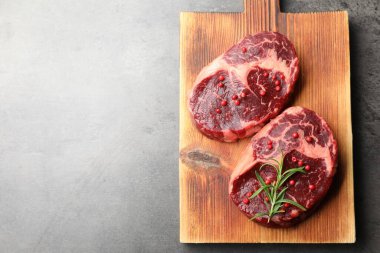 Gri desenli masa üzerinde çiğ et ve baharat parçaları, üst manzara. Metin için boşluk