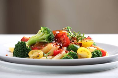 İçerideki beyaz masada sebzeli ve baharatlı makarna.