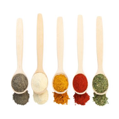 Tahta kaşıklardaki farklı aromatik baharatlar beyaz, üstten bakıldığında izole.