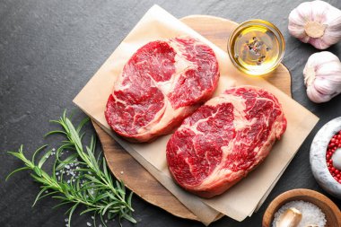 Çiğ et parçaları ve baharatlar siyah masanın üzerinde, düz yatıyordu.