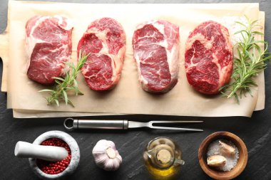 Çiğ et, baharat ve çatal parçaları siyah masaya, düz yatıyordu.