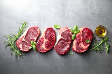 Çiğ et parçaları ve baharatlar gri masada, düz yatıyordu.