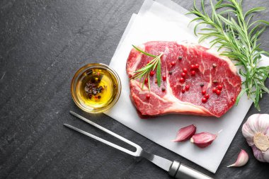 Bir parça çiğ et, baharat ve siyah masanın üzerine oyma çatal. Metin için boşluk