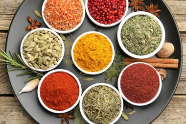 Ahşap masada farklı aromatik baharatlar, üst görünüm.