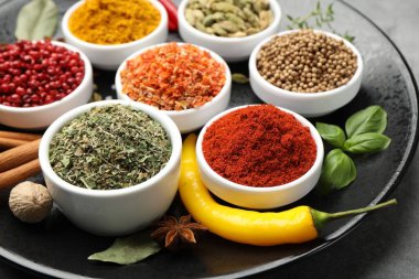 Gri masada farklı aromatik baharatlar, yakın plan.