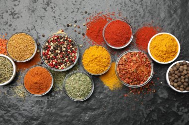 Tabaklardaki farklı aromatik baharatlar koyu masada, düz yerde.