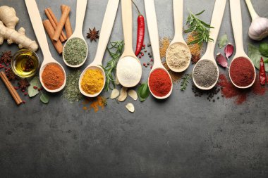 Gri masadaki kaşıklarda bir sürü farklı baharat var. Metin için boşluk