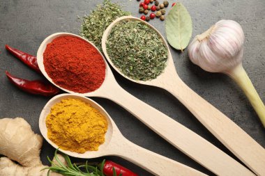 Gri masadaki kaşıklardaki farklı baharatlar düzdü.