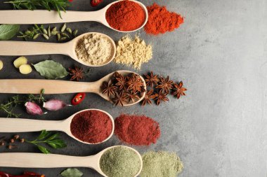 Gri masadaki kaşıklardaki farklı baharatlar düzdü.