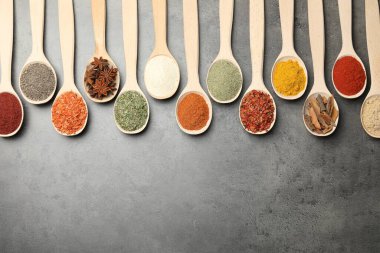 Gri masadaki kaşıklarda bir sürü farklı baharat var. Metin için boşluk