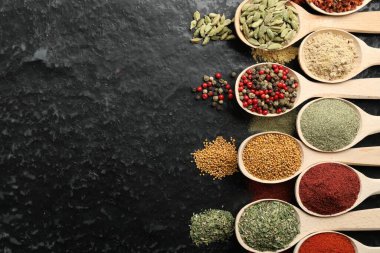 Siyah masadaki kaşıklarda bir sürü farklı baharat var. Metin için boşluk