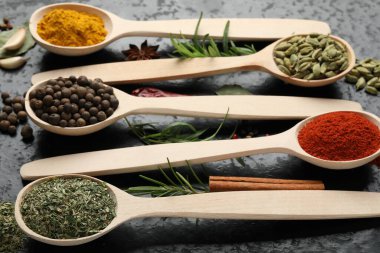 Siyah masadaki kaşıklardaki farklı baharatlar, yakın plan.