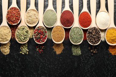 Siyah masadaki kaşıklarda bir sürü farklı baharat var.