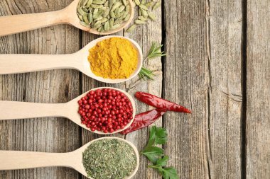 Tahta masadaki kaşıklardaki farklı aromatik baharatlar. Metin için boşluk