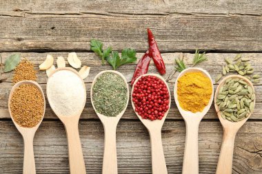 Tahta masada, düz yerde, kaşıklardaki farklı aromatik baharatlar.