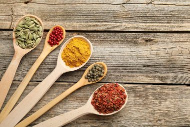 Tahta masadaki kaşıklardaki farklı aromatik baharatlar. Metin için boşluk