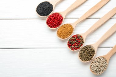 Beyaz ahşap masadaki kaşıklardaki farklı aromatik baharatlar. Metin için boşluk