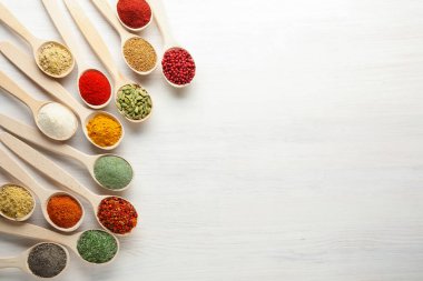 Beyaz ahşap masadaki kaşıklardaki farklı aromatik baharatlar. Metin için boşluk