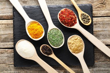 Tahta masada, düz yerde, kaşıklardaki farklı aromatik baharatlar.