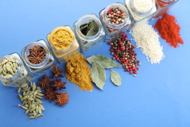 Mavi arka planda kavanozlarda farklı aromatik baharatlar var.