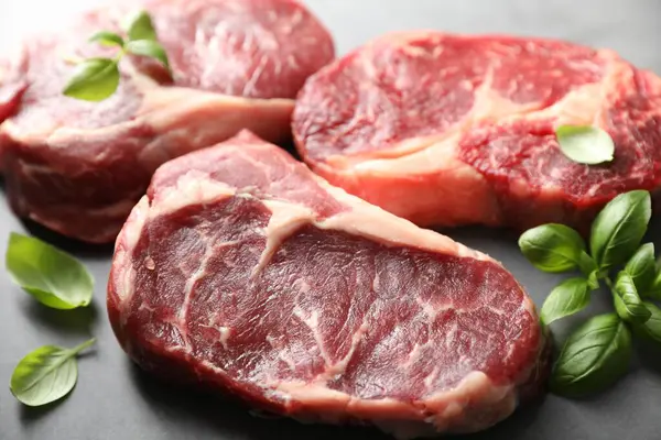 Çiğ et ve fesleğen parçaları gri masada, yakın plan.