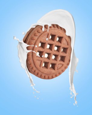 Açık mavi arka planda lezzetli kurabiye ve süt sıçraması