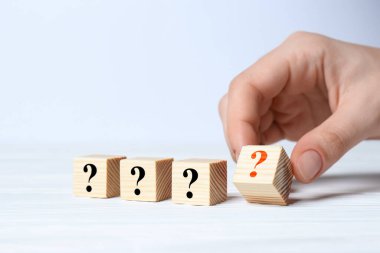 Beyaz masada soru işaretiyle küplere dokunan kadın, yakın plan.