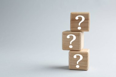 Açık gri arkaplanda soru işaretleri olan tahta küplerin yığını, metin için boşluk