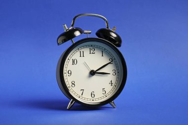 Mavi arkaplanda bir siyah alarm saati