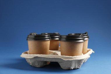 Kağıt kahve bardakları mavi arka planda karton tutacakta. Metin için boşluk