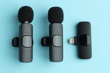 Lavalier mikrofonlar ve açık mavi zemin üzerinde kablosuz alıcı, düz yatıyordu