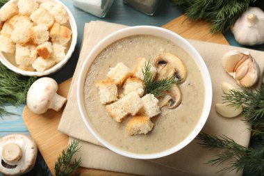 Lezzetli mantar kremalı çorba, kızarmış ekmek, dereotu ve malzemeler mavi masada.
