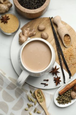 Aromatik Masala çayı fincanda, kahverengi şeker, kuru yapraklar ve baharatlar beyaz mermer masada, düz yatıyordu.