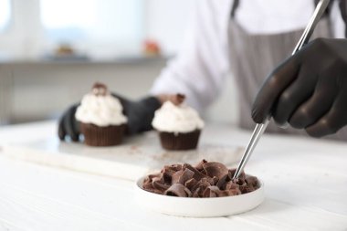 Mutfaktaki beyaz ahşap masada çikolata traşlı lezzetli kekler, seçici odak noktası.