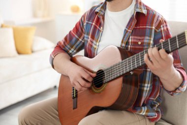 Sandalyede gitar çalan adam, yakın plan.