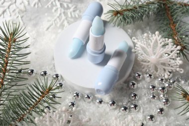 Nemlendirici dudak kremleri, Noel dekorasyonu ve yapay kar üzerindeki köknar ağacı dalları, yakın plan. Kış bakımı