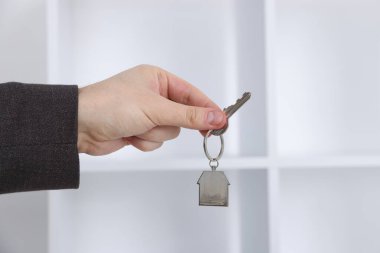 Emlakçının elinde ev şeklindeki anahtarlık var.
