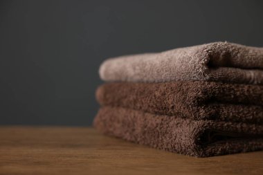 Ahşap masadaki temiz havlular koyu gri arka plana karşı, yakın plan. Metin için boşluk