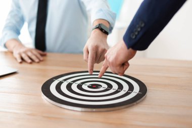 İçerideki ahşap masada dart tahtasına bakan adamlar, yakın plan.