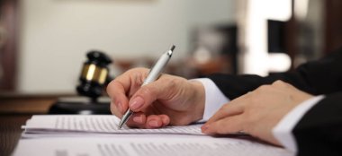 Yargıç, kapalı bir masada evrak ile çalışıyor, yakın plan. Pankart tasarımı