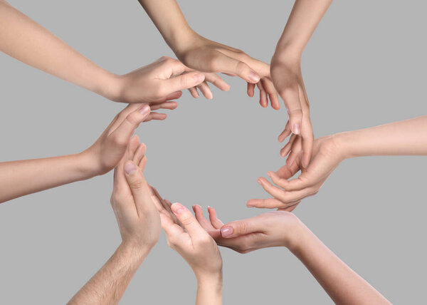 People making circle with their hands on grey background, closeup. Unity, partnership, cooperation