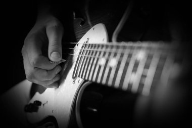 Karanlıkta gitar çalan adam, yakın plan. Siyah ve beyaz etkisi