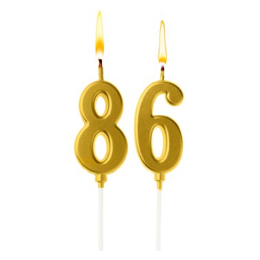 Beyaz arka planda 86 numarayı besteleyen yanan altın pasta mumları. Doğum günü veya diğer özel tarihler için şenlik dekorasyonu