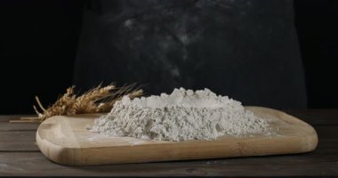 Ahşap masada siyah arkaplana karşı un yığınına yumurta eklemek, yakın plan. Para kazanmak.