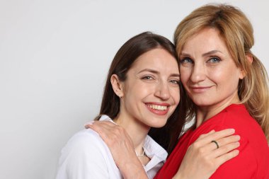 Anne ve kızı beyaz arka planda sarılıyorlar. Metin için boşluk