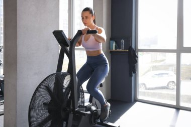 Spor salonunda spor bisikleti eğitimi alan atletik kadın.