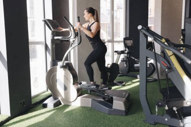 Spor salonunda eliptik makine eğitimi alan atletik kadın.